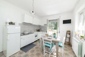 een keuken met witte kasten en een tafel met stoelen bij Reginella al mare in Policastro Bussentino