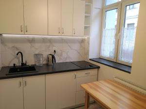 a kitchen with white cabinets and a sink and a table at Apartament Pijarska in Nowy Sącz