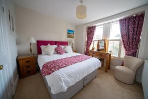 a bedroom with a large bed and a chair at Brookdale House in Wadebridge