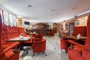 un restaurante con cabinas rojas, mesas y sillas en Bristol Hotel, en Krasnodar