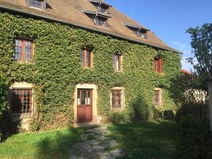 a building covered in ivy with a wooden door at Maison de Charme "Le Moulin d'Hagenthal" - Chambre Baroque in Hagenthal-le-Bas