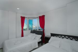 1 dormitorio con 2 camas y una ventana con cortinas rojas en Horizon Apartment, en Cartagena de Indias