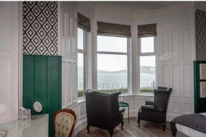 a bedroom with a bed and two chairs and a window at Witchwood House in Oban
