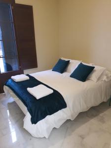 a large bed with blue and white pillows on it at Habitaciones Casa Sevillana Centro in Seville