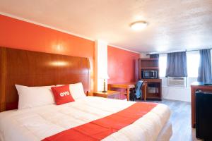 1 dormitorio con 1 cama grande y pared de color naranja en Hotel O Atlanta Airport Jonesboro/Morrow I-75, en Jonesboro