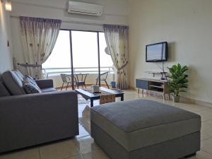 a living room with a couch and a tv at Sea Front The Regency - Pool open in Port Dickson