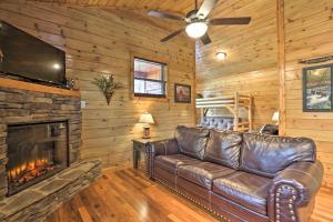 een leren bank in een woonkamer met een open haard bij Rustic Pigeon Forge Cabin with Hot Tub Near Town! in Pigeon Forge