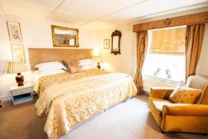 um quarto com uma cama, uma cadeira e uma janela em The Tankerville Arms em Eglingham
