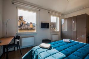 a bedroom with a blue bed and a desk and windows at Residenza Benizzi rooms in the heart of Florence in Florence