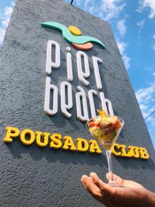 uma pessoa segurando uma sobremesa em frente a uma placa em PIER BEACH CLUB em Cabo Frio