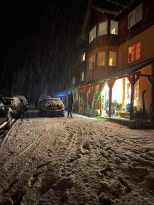 een man die 's nachts over een met sneeuw bedekte straat loopt bij Cabana Liliana in Arieşeni