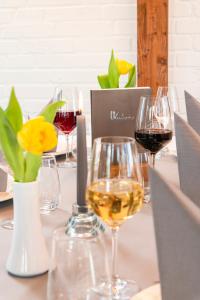 ノイキルヒェンにあるHotel-Klanxbüller-Stubenのワインと花のグラスを盛り付けたテーブル