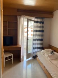 a bedroom with a bed and a desk and a window at Villa Del Rosensuite in Pinzolo +15 photos