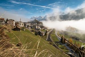 a small town on a hill with fog in the mountains at Attika Wohnung 7546 Ardez in Ardez