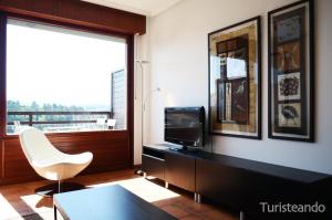 a living room with a tv and a white chair at Dúplex Marisma de Pombo - Parking privado y vistas inolvidables in San Vicente de la Barquera