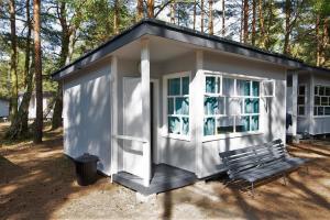 a small white shed with a bench and trees at Camp Bursztynowy Las in Gdańsk