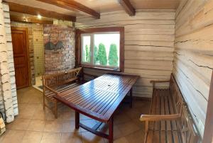una mesa de madera y bancos en una habitación con ventana en Rustic private Cabin in woods w/ Sauna & Pool en Vilna