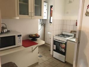 a small kitchen with a stove and a microwave at Departamento amoblado en pleno centro, con cochera in Bahía Blanca