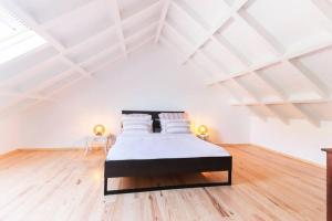 a bedroom with a bed in a white attic at CAPARICA BEACH VILLA in Trafaria