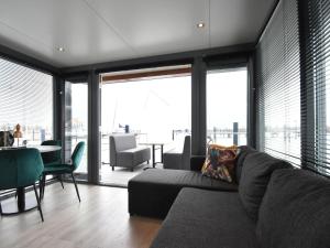 a living room with a couch and a table and windows at Beautiful Houseboat in the harbour of Volendam near Centre in Volendam