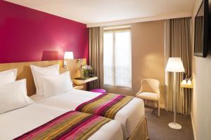 a hotel room with two beds and a purple wall at Hôtel Cordelia Opéra-Madeleine in Paris