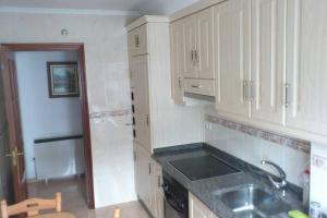a kitchen with white cabinets and a sink at Alquiler Vacacional Noia in Noya