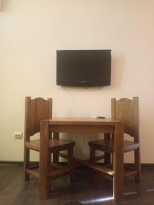 een houten tafel met twee stoelen en een televisie aan de muur bij Lux na Osipenko in Oezjhorod
