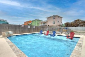 a swimming pool with red and blue chairs and a fence at Yachta-Yachta in Port Aransas