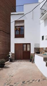 Casa blanca con puerta de madera y ventana en Casa Carmen, en Laroles