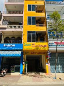 um edifício amarelo numa rua da cidade com lojas em Khách sạn Duy Hoàng em Buon Ma Thuot