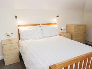 a bedroom with a bed with two dressers and two night stands at Dunromin in Llandudno