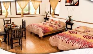 a bedroom with two beds and a table and a desk at Posada Acaxiloco in Cuetzalán del Progreso