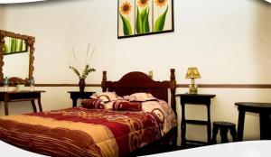 1 dormitorio con 1 cama, 2 mesas y espejo en Posada Acaxiloco, en Cuetzalán del Progreso
