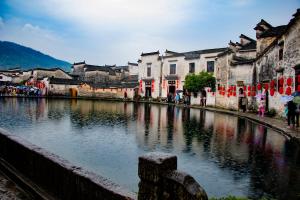 Un río en una ciudad con edificios y gente alrededor en 杏竹斋客栈, en Yi