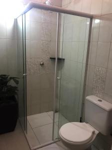 a bathroom with a glass shower with a toilet at Suítes Itaigara a 80 metros da praia do Mariscal in Bombinhas