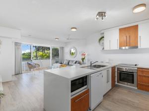 Una cocina con electrodomésticos blancos y una sala de estar. en Picture Point 4 - 500m to Hastings St & Noosa Beach, en Noosa Heads