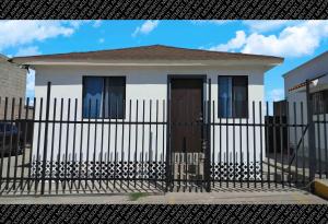 une petite maison blanche avec une clôture noire dans l'établissement The White Bungalow, à Rosarito
