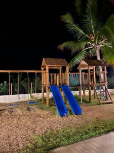 une aire de jeux avec un toboggan bleu et une maison dans l'établissement Village Itacimirim, Pé na areia, Excelente 7B, à Itacimirim