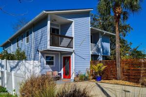 a white house with a red door and a palm tree at Seventh Seas half mile to the beach pet friendly Near to the Mayo Clinic - UNF - TPC Sawgrass - Convention Center - Shopping Malls - Under 3 Hours from DISNEY in Jacksonville Beach