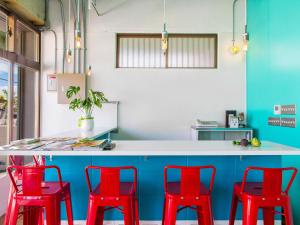 cocina con sillas rojas y encimera azul en Seawall Hostel, en Chatan