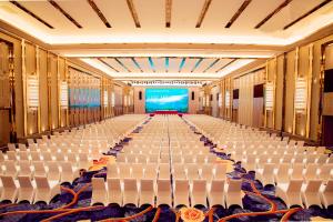 an empty room with white chairs and a stage at Easeland Hotel Guangzhou in Guangzhou