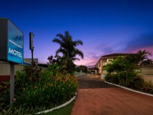 a motel sign in front of a building with a palm tree at Kennedy Drive Airport Motel in Tweed Heads