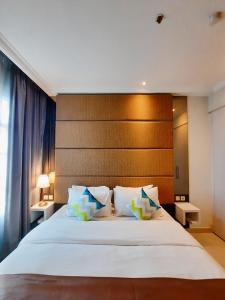 um quarto com uma grande cama branca e uma cabeceira em madeira em The Bellezza Hotel Suites em Jacarta