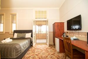 Schlafzimmer mit einem Bett, einem Schreibtisch und einem TV in der Unterkunft Hydro Hotel in Leeton
