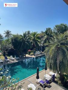 un homme debout à côté d'une piscine bordée de palmiers dans l'établissement Marina Villa, à Lamai