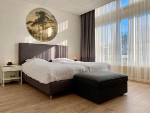 a bedroom with a bed with a ottoman and a large window at Apartment Kerkplein 7A in Zandvoort