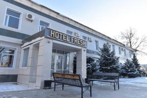 a hotel with two benches in front of it at Hotel FRESH in Aktobe