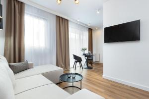 a living room with a white couch and a flat screen tv at Moduo Apartments Warsaw by Renters Prestige in Warsaw