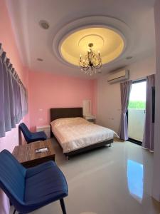 een slaapkamer met een bed, een tafel en een kroonluchter bij 葳葳民宿 in Magong