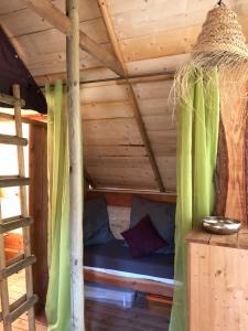 a bed in a wooden cabin with green curtains at Lodges en Provence - Ecogîtes & Restaurant insolites in Richerenches